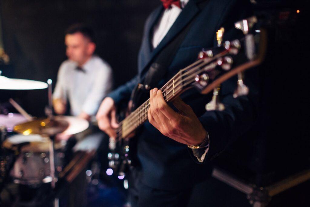 Mann spielt auf der Gitarre, Schlagzeuger im Hiuntergrund, Musik und Unterhaltung