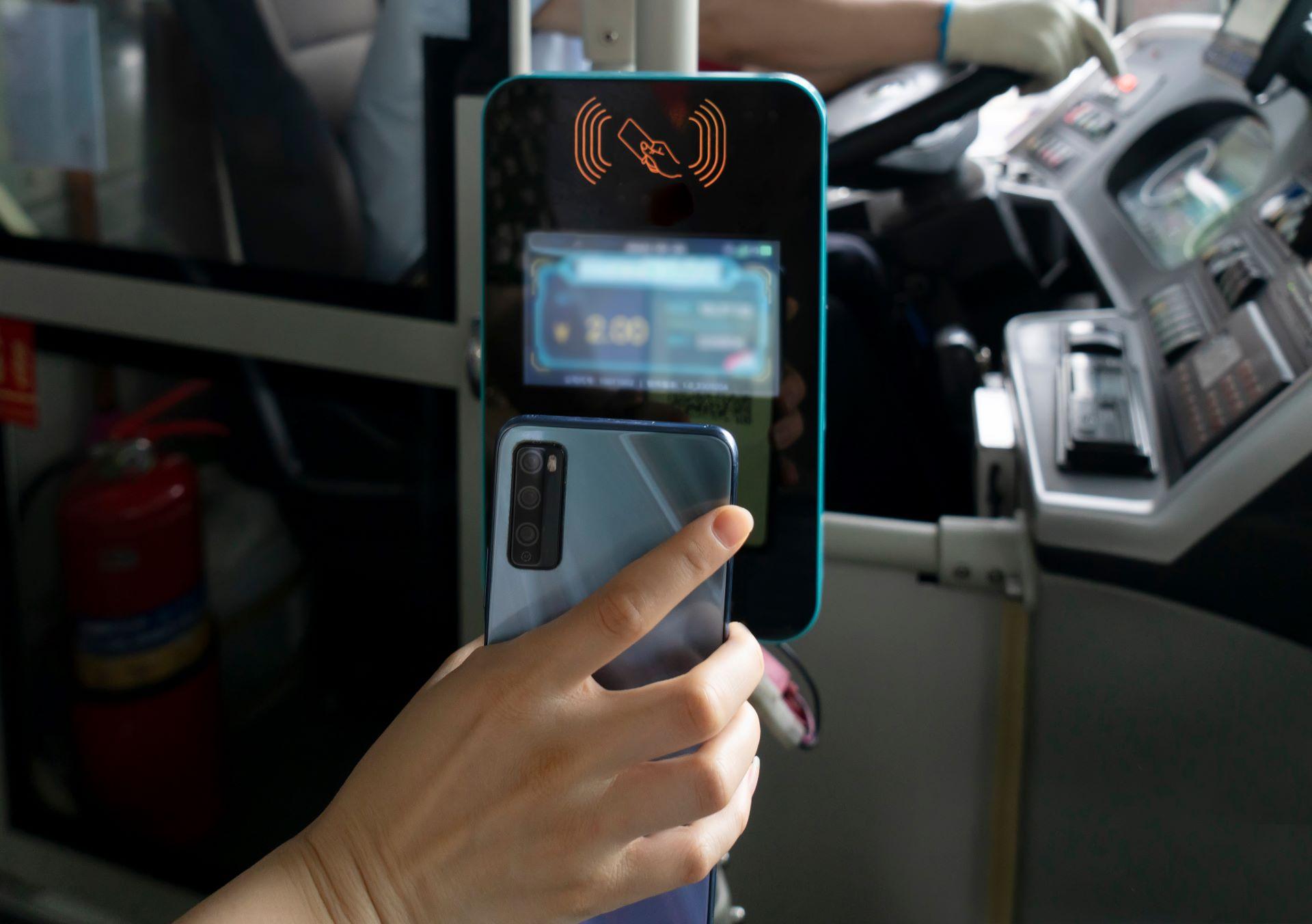 Smartphone wird an Kartenleser im Bus gehalten