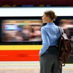 Frau mit Rucksack wartet am Bahnsteig