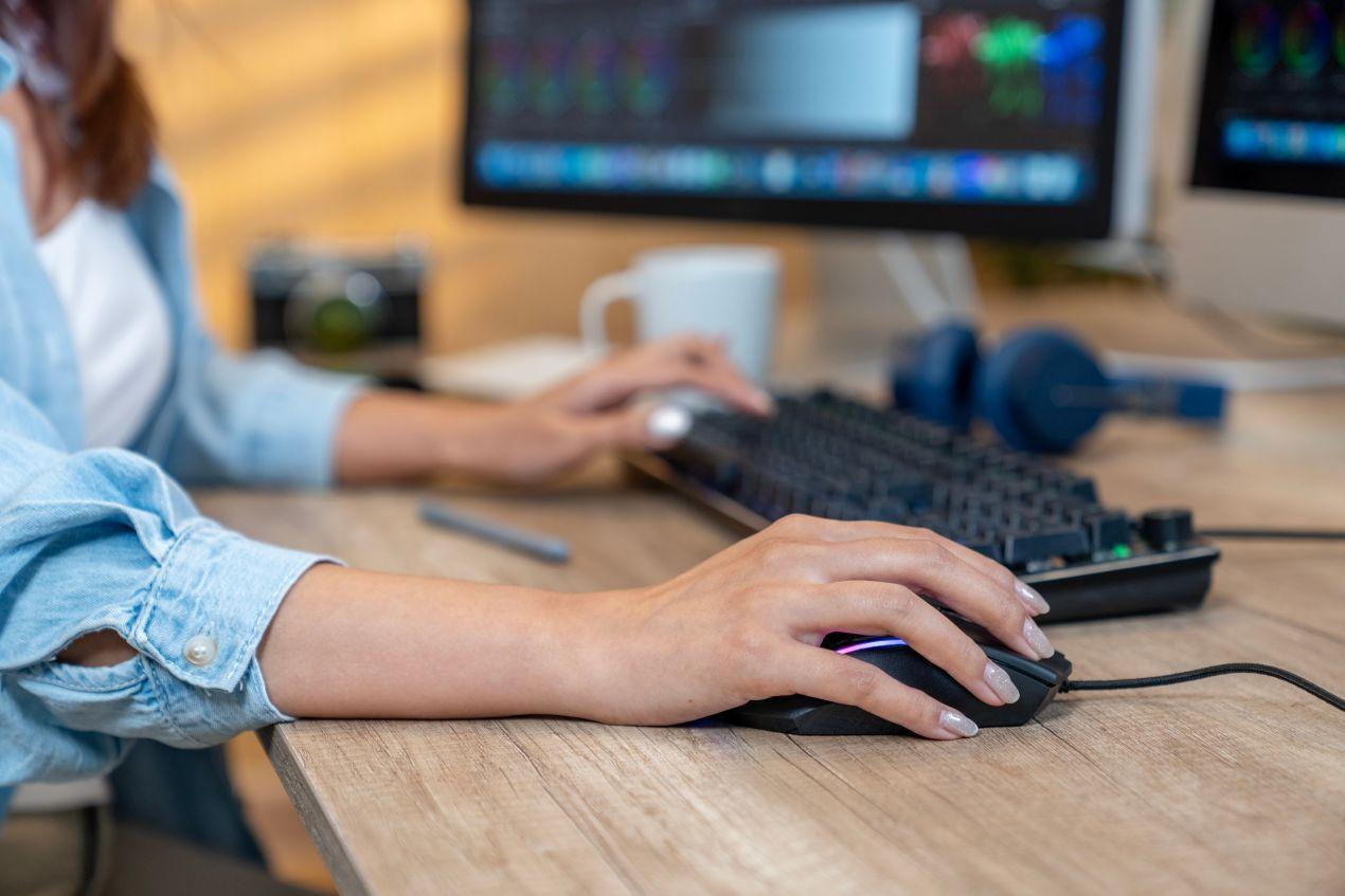 Frau arbeitet am Computer mit Maus – digitales Lektorat am Arbeitsplatz