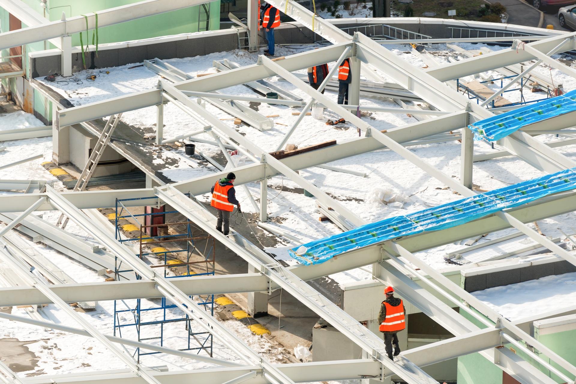 Arbeiter montieren Stahlkonstruktion im Schnee auf Dach | Heizanhänger