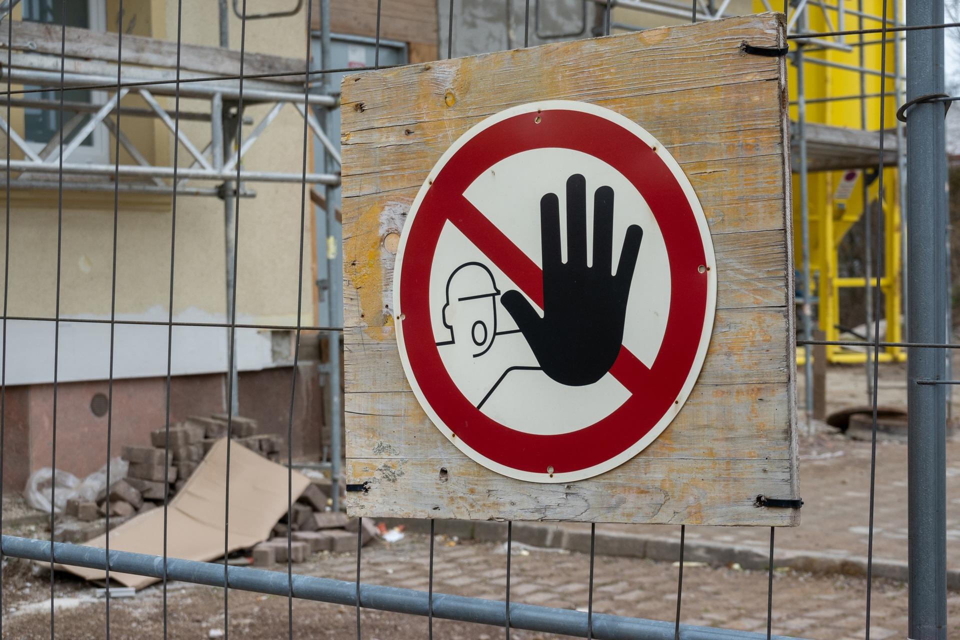 Stopp-Warnschild auf Bauzaun vor Gerüst | Heizanhänger